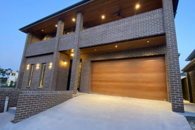 This is an example of an expansive modern two-storey brick house exterior in Sydney with a hip roof and a tile roof.