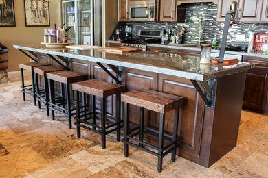Mid-sized mountain style single-wall travertine floor and beige floor open concept kitchen photo in Austin with an undermount sink, raised-panel cabinets, medium tone wood cabinets, multicolored backsplash, mosaic tile backsplash, stainless steel appliances, an island and stainless steel countertops