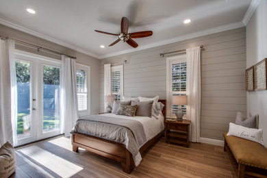 Example of a mid-sized transitional master brown floor and shiplap wall bedroom design in Other with gray walls, a standard fireplace and a brick fireplace