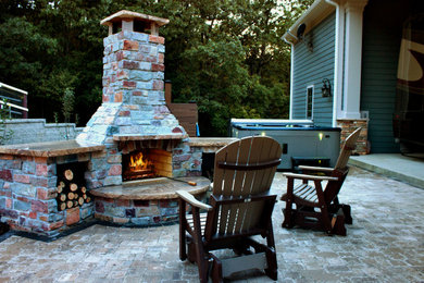 Example of a mid-sized beach style backyard concrete paver patio design in St Louis with a fireplace