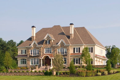 Huge elegant two-story stone exterior home photo in Philadelphia with a hip roof