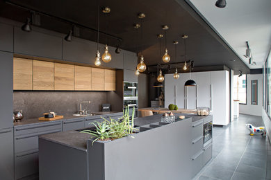Réalisation d'une cuisine ouverte parallèle et encastrable design avec un évier intégré, un plan de travail en granite, une crédence beige et îlot.