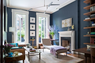 Large transitional open concept medium tone wood floor living room library photo in New York with blue walls, a standard fireplace and no tv