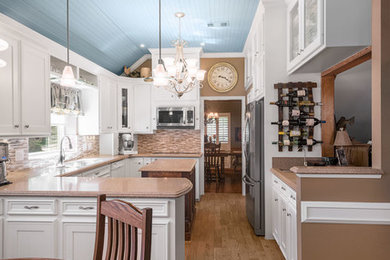 Mid-sized arts and crafts u-shaped light wood floor and brown floor eat-in kitchen photo in Houston with a double-bowl sink, white cabinets, marble countertops, beige backsplash, glass tile backsplash, stainless steel appliances, an island and recessed-panel cabinets