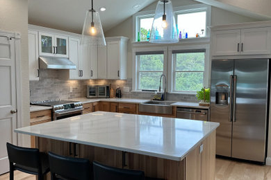 Inspiration for a large craftsman l-shaped vinyl floor, beige floor and vaulted ceiling open concept kitchen remodel in Other with a drop-in sink, raised-panel cabinets, white cabinets, quartzite countertops, gray backsplash, cement tile backsplash, stainless steel appliances, an island and white countertops