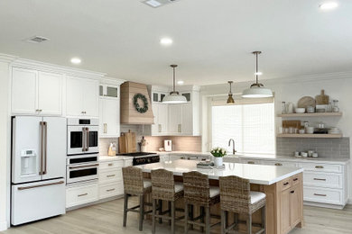 Inspiration for a large coastal l-shaped eat-in kitchen remodel in Los Angeles with white cabinets and an island