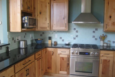 Example of a mid-sized transitional l-shaped ceramic tile and beige floor enclosed kitchen design in Denver with recessed-panel cabinets, light wood cabinets, blue backsplash, stainless steel appliances, an island, an undermount sink, granite countertops and ceramic backsplash