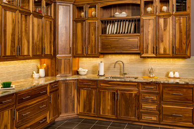 Kitchen - mid-sized traditional ceramic tile and gray floor kitchen idea in Other with an undermount sink, recessed-panel cabinets, dark wood cabinets, granite countertops, brown backsplash and glass tile backsplash