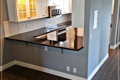Beach style u-shaped porcelain tile kitchen photo in Miami with a double-bowl sink, shaker cabinets, white cabinets, granite countertops, white backsplash, subway tile backsplash and stainless steel appliances