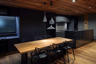 Inspiration pour une cuisine parallèle minimaliste avec des portes de placard grises, une crédence grise, îlot et plan de travail noir.