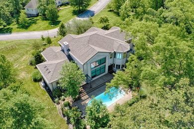 Inspiration for a large contemporary beige three-story stucco house exterior remodel in Other with a hip roof and a shingle roof