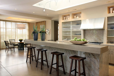 Large trendy single-wall concrete floor and beige floor open concept kitchen photo in San Francisco with an undermount sink, flat-panel cabinets, light wood cabinets, concrete countertops, beige backsplash, marble backsplash, stainless steel appliances and an island