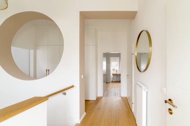 Small modern hallway in Other with white walls, light hardwood floors and beige floor.