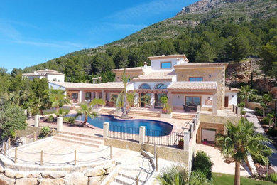 Diseño de fachada de casa beige clásica extra grande de tres plantas con revestimiento de piedra, tejado a cuatro aguas y tejado de teja de barro