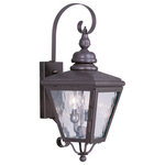Livex Lighting - Cambridge Outdoor Wall Lantern, Bronze - This stylish bronze outdoor wall lantern is a great way to update your home's exterior decor. A flat metal curved arm attaches the solid brass decorative housing to the square backplate while clear water glass protects the two bulbs.