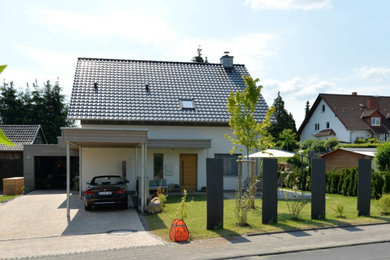 Modelo de fachada de casa tradicional de tamaño medio de dos plantas con revestimiento de estuco, tejado a dos aguas y tejado de teja de barro