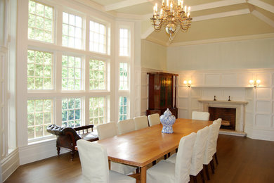 Photo of an expansive traditional separate dining room in New York with white walls, medium hardwood floors, a standard fireplace and a stone fireplace surround.