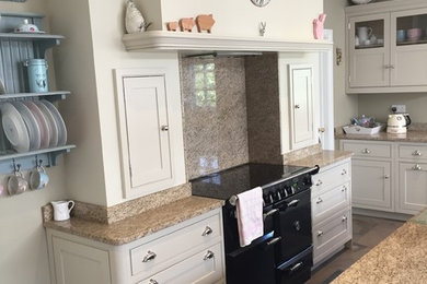 This is an example of an expansive classic single-wall kitchen/diner in Other with a belfast sink, shaker cabinets, beige cabinets, granite worktops, multi-coloured splashback, black appliances, porcelain flooring, an island, multi-coloured floors and multicoloured worktops.