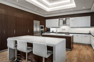 Example of a huge minimalist u-shaped medium tone wood floor and brown floor eat-in kitchen design in Miami with a double-bowl sink, flat-panel cabinets, dark wood cabinets, quartzite countertops, white backsplash, stainless steel appliances and two islands