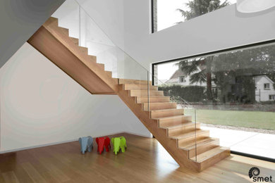 This is an example of a modern wood l-shaped staircase in Brussels with wood risers and glass railing.