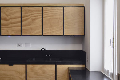 Ispirazione per una piccola cucina contemporanea chiusa con ante in legno chiaro, parquet chiaro, pavimento beige e top nero