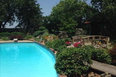 Photo of a large transitional partial sun backyard brick landscaping in Other.
