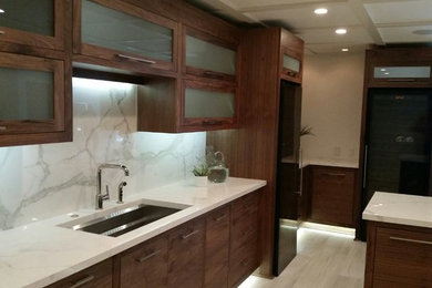Mid-sized trendy l-shaped light wood floor enclosed kitchen photo in Nashville with an undermount sink, glass-front cabinets, dark wood cabinets, marble countertops, white backsplash, marble backsplash, stainless steel appliances and a peninsula