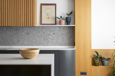 Imagen de cocinas en L nórdica grande abierta con fregadero de doble seno, puertas de armario grises, encimera de cuarzo compacto, salpicadero verde, salpicadero de azulejos de porcelana, electrodomésticos negros, suelo de baldosas de porcelana, una isla, suelo gris y encimeras blancas