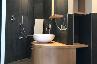 Small contemporary bathroom with a curbless shower, a wall-mount toilet, black tile, black walls, a console sink, laminate benchtops, black floor and an open shower.