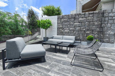 Medium sized contemporary back formal full sun garden seating for summer in Hong Kong with natural stone paving and a stone fence.