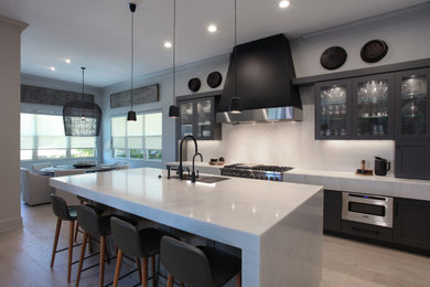 Foto di una grande cucina design con lavello sottopiano, ante di vetro, ante in legno bruno, paraspruzzi bianco, elettrodomestici in acciaio inossidabile, pavimento beige e top bianco
