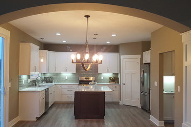Inspiration for a mid-sized arts and crafts u-shaped eat-in kitchen in Grand Rapids with an undermount sink, shaker cabinets, white cabinets, quartzite benchtops, white splashback, glass tile splashback, stainless steel appliances, laminate floors and with island.