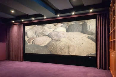 Cette image montre une grande salle de cinéma traditionnelle fermée avec moquette et un écran de projection.