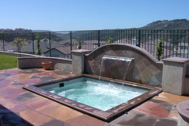 Inspiration for a mid-sized contemporary backyard stone and rectangular hot tub remodel in Orange County