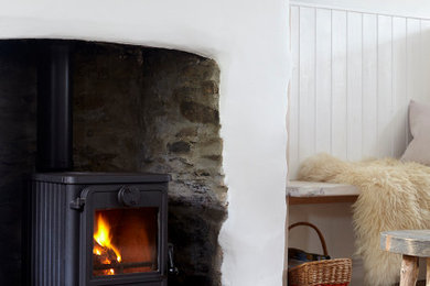 Inspiration for a medium sized open plan living room in Devon with white walls, light hardwood flooring, a wood burning stove and a stone fireplace surround.