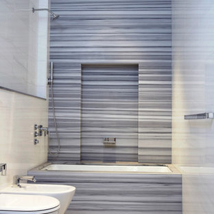 Idee per una stanza da bagno moderna con vasca sottopiano, vasca/doccia, lastra di pietra e piastrelle grigie