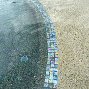 View of tile and multi colored pool and sunshelf