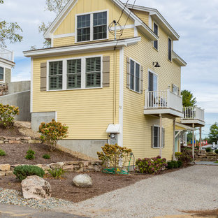 Klassisk inredning av ett stort gult hus, med tre eller fler plan, vinylfasad och mansardtak