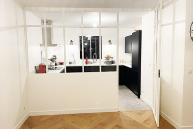 パリにあるラグジュアリーな中くらいなコンテンポラリースタイルのおしゃれなキッチン (ドロップインシンク、フラットパネル扉のキャビネット、青いキャビネット、白いキッチンパネル、黒い調理設備、テラコッタタイルの床、アイランドなし、グレーの床、白いキッチンカウンター、窓) の写真