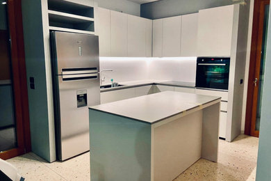 Immagine di una cucina contemporanea di medie dimensioni con lavello sottopiano, ante lisce, top in quarzo composito, paraspruzzi bianco, elettrodomestici neri e top grigio