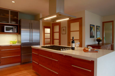 Eat-in kitchen - mid-sized contemporary l-shaped medium tone wood floor eat-in kitchen idea in Seattle with a double-bowl sink, glass-front cabinets, medium tone wood cabinets, quartz countertops, blue backsplash, glass tile backsplash, stainless steel appliances and an island