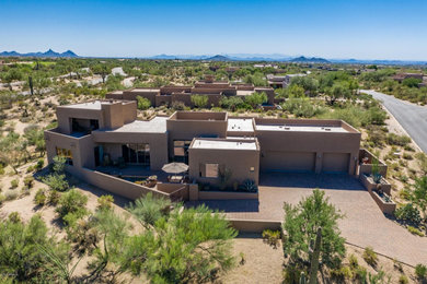 Example of a huge minimalist beige two-story stucco exterior home design in Phoenix with a mixed material roof