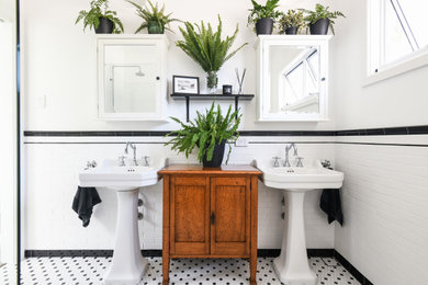 Klassisches Badezimmer mit schwarz-weißen Fliesen, weißer Wandfarbe, Mosaik-Bodenfliesen, Sockelwaschbecken und Doppelwaschbecken in Sydney
