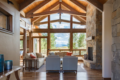Inspiration for a large rustic open concept medium tone wood floor and brown floor living room remodel in Denver with a standard fireplace, a stone fireplace and no tv