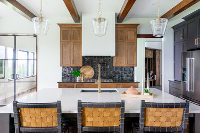 Inspiration for a large l-shaped exposed beam open concept kitchen remodel in Kansas City with an undermount sink, shaker cabinets, medium tone wood cabinets, quartz countertops, black backsplash, stainless steel appliances, an island and white countertops