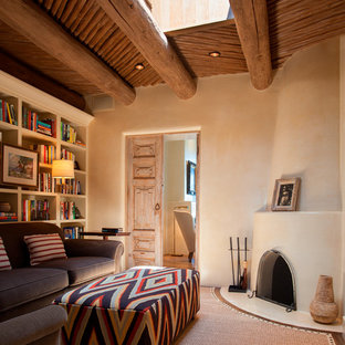 Fernseherlose, Abgetrennte Mediterrane Bibliothek mit beiger Wandfarbe, dunklem Holzboden, Kaminofen und verputztem Kaminsims in Albuquerque