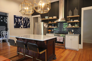 Example of a large classic l-shaped medium tone wood floor and brown floor open concept kitchen design in Atlanta with an undermount sink, shaker cabinets, white cabinets, black backsplash, subway tile backsplash, stainless steel appliances and an island