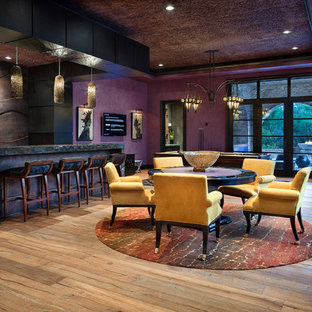 Offenes Mediterranes Wohnzimmer mit Hausbar, lila Wandfarbe, hellem Holzboden und Wand-TV in Houston