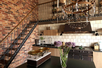 Inspiration for a mid-sized industrial single-wall kitchen in Moscow with an undermount sink, flat-panel cabinets, light wood cabinets, granite benchtops, beige splashback, ceramic splashback, black appliances and black benchtop.
