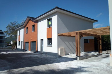 Cette photo montre une façade de maison mitoyenne moderne à un étage avec un toit gris.